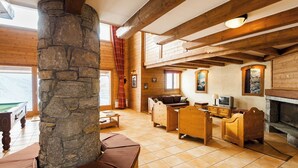 Un interior acogedor y rústico con un pilar de piedra, muebles de madera, una chimenea y un televisor.