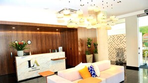 A hotel reception area with a marble counter, a sofa with cushions, and hanging light fixtures.