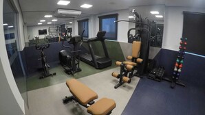 A gym with exercise equipment, a bench, and a mirror.