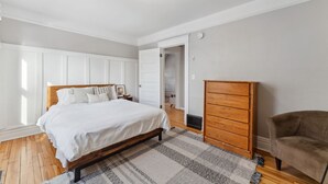 Ein Schlafzimmer mit einem hölzernen Bett, einer Holzkommode und einem Sessel.