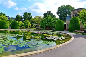 A serene garden with a pond surrounded by neatly trimmed hedges and benches. - Lo Exclusive Stuttgart – City apartment with terrace & garden (Stuttgart)