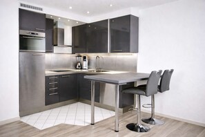 A modern kitchen with a built-in oven, a sink, and a bar stool. - Lo Exclusive Stuttgart – City apartment with terrace & garden (Stuttgart)