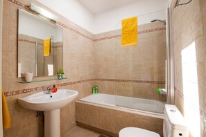 Ein Badezimmer mit Waschbecken, Spiegel, Badewanne und Toilette.