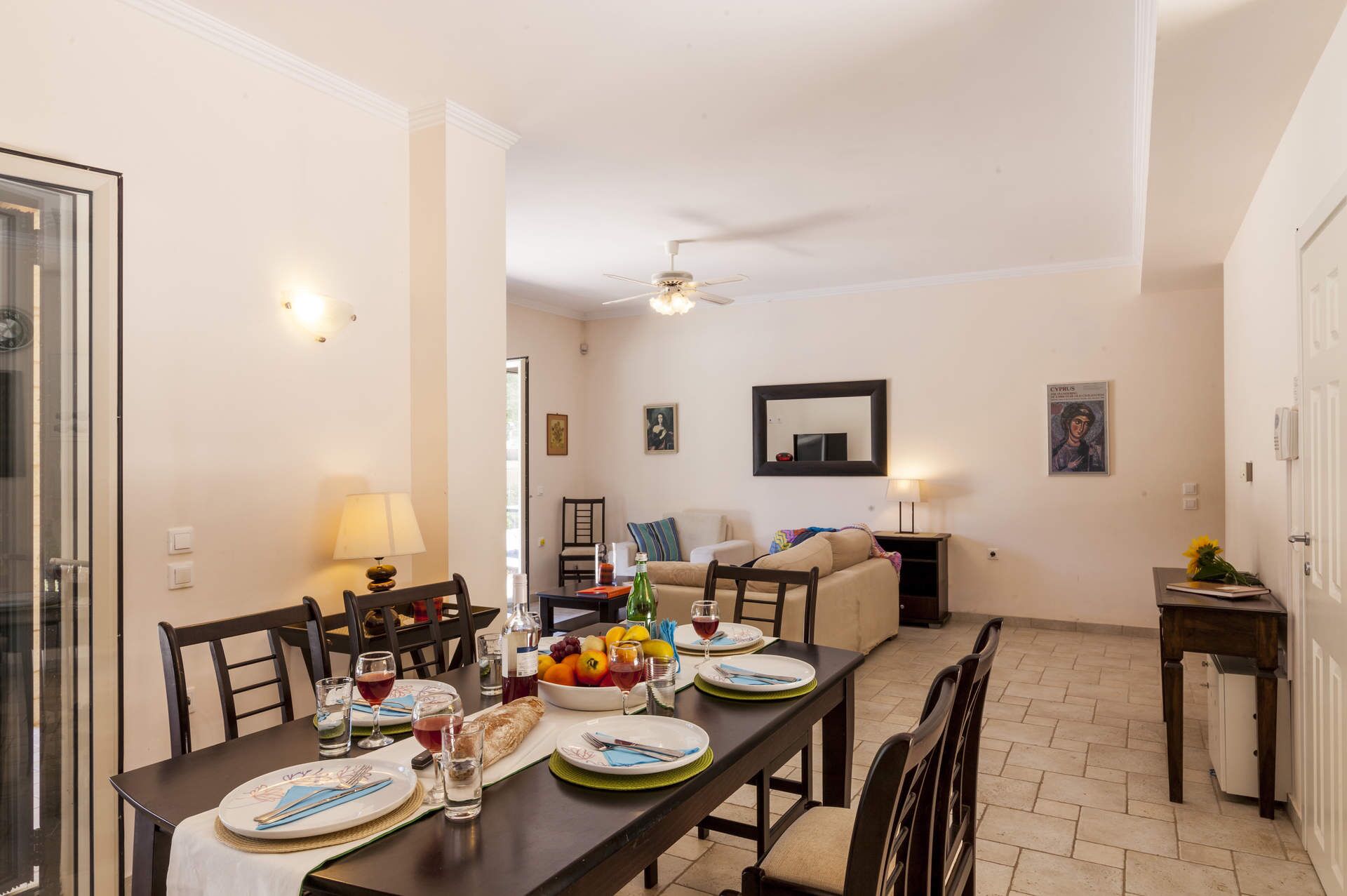 A dining area with a table set for four, a ceiling fan, and a view into a living room.