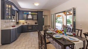 A modern kitchen with dark cabinets, a central island, and a dining area with a table set for four.