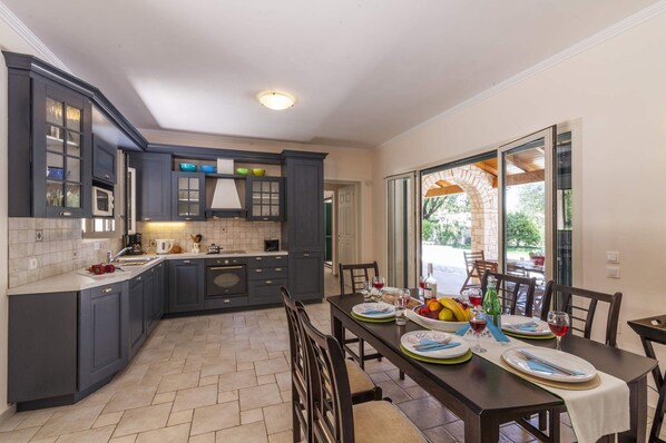 A modern kitchen with dark cabinets, a central island, and a dining area with a table set for four.