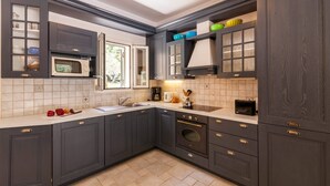 A modern kitchen with dark cabinetry, a built-in microwave, a stove, and a window.