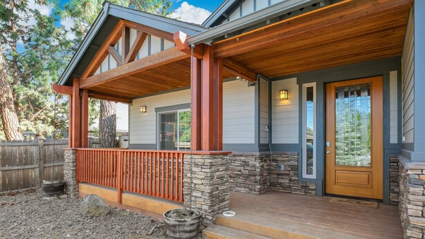 A house with a wooden porch, stone steps, and a front door with a glass panel. - Spacious 1 Level Sisters Home - Walk to Downtown (Sisters)