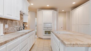A modern kitchen with white cabinetry, a large island, a microwave, and an oven. - Spacious 1 Level Sisters Home - Walk to Downtown (Sisters)
