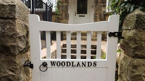 A white gate with the name "WOODLANDS" on it, set against a stone wall. - Woodlands (Matlock)