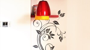 A room with a clock, a red pendant light, a decorative wall, and a table with a floral tablecloth. - Appartamento Stella – spazioso e moderno, vicino al centro di Bergamo (Bergamo)
