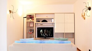 A modern living room with a flat-screen TV, built-in shelving, and a sofa. - Appartamento Stella – spazioso e moderno, vicino al centro di Bergamo (Bergamo)