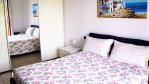 A bedroom with a bed, a nightstand, and a painting of a coastal scene. - Appartamento Stella – spazioso e moderno, vicino al centro di Bergamo (Bergamo)