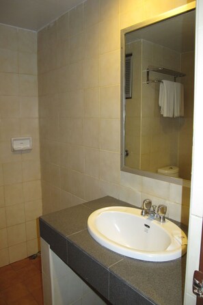 A bathroom with a white sink, a mirror, and a towel rack. - Palm Garden Hotel (Pattaya)