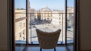 A room with a large window, a patterned chair, and a view of a cityscape. - Abalto Suites & Rooms (Lecce)