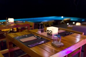 A dining table set with cutlery, napkins, a candle, and a decorative cube. - Kura Design Villas (Ballena)