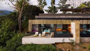 A modern house with a pool, lounge chairs, and a view of the surrounding greenery. - Kura Design Villas (Ballena)