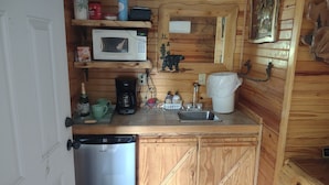 A compact kitchen with a microwave, coffee maker, sink, and wooden cabinets. - Cozy 1 Room Cabin (Mountain View)