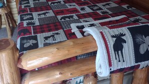 A wooden bed with a quilt featuring animal prints, a wooden headboard, and a painting of deer. - Cozy 1 Room Cabin (Mountain View)