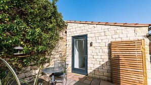 A stone building with a door, a small patio with a table and chair, and a wooden fence. - The Pigsty - sleeps 2 guests  in 1 bedroom (York)
