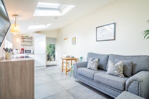 A modern living space with a kitchen, dining area, and a sofa. - The Pigsty - sleeps 2 guests in 1 bedroom (York)