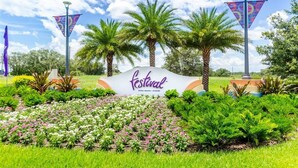 Schild für den Festival Resort in Orlando, umgeben von üppiger Vegetation und Palmen.