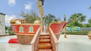 Eine Holztreppe führt zu einem schiffartigen Wasserspiel mit einer Fontäne.