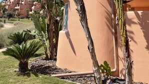 Un bâtiment à la façade rose, entouré de bananiers et d’autres plantes vertes.