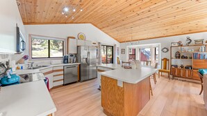 A spacious kitchen with wooden ceiling, stainless steel appliances, and a central island.