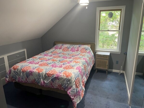A bedroom with a bed, a nightstand, a window, and a door.