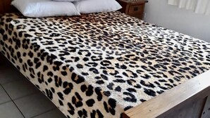 Un lit avec une tête de lit en bois, une couvre-lit à motifs léopard et une table de chevet avec une lampe.