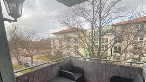 Un balcon doté de meubles en osier et offrant une vue sur les immeubles.