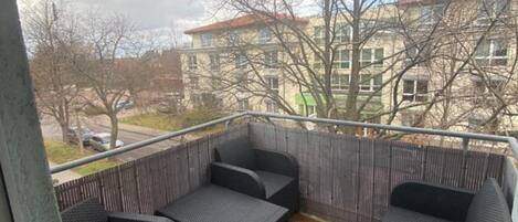A balcony with wicker furniture and a view of buildings.