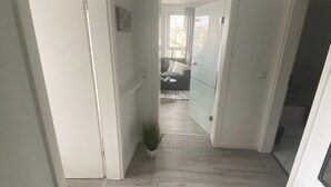 Un couloir doté d’un plancher en bois, d’une plante en pot et d’un luminaire suspendu.
