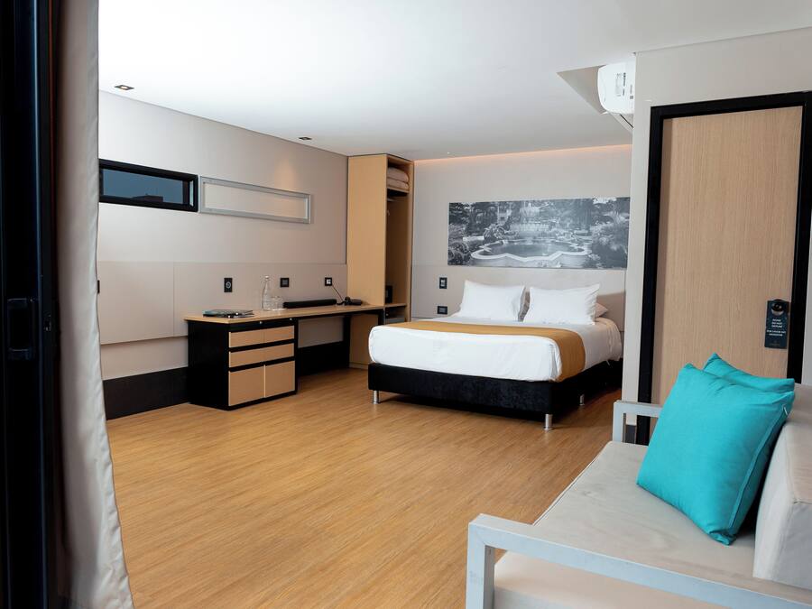 Een moderne hotelkamer met een bed, een bureau, een stoel en een bank.
