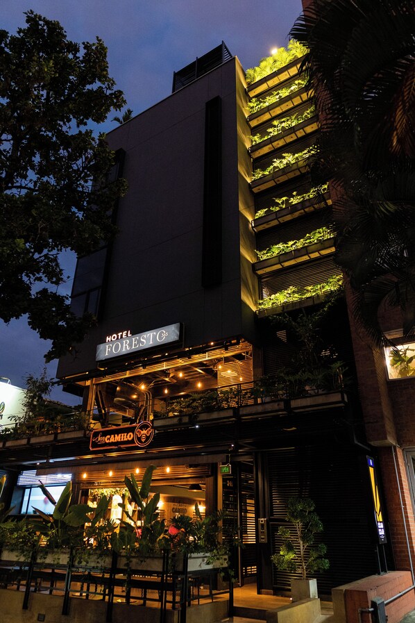 Un hotel con fachada moderna, zona de estar al aire libre y jardines verticales.