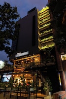 A hotel with a modern facade, outdoor seating area, and vertical gardens.