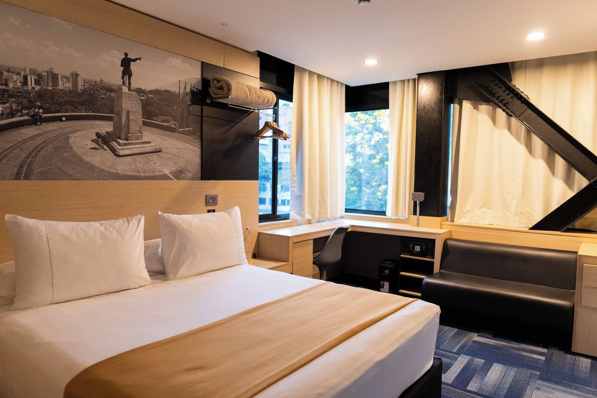 A hotel room with a bed, desk, and seating area.