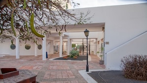 Une cour avec un banc, un lampadaire et un pot de fleurs.