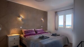 Une chambre à coucher avec un lit, des tables de chevet, une lampe et une fenêtre avec des rideaux.