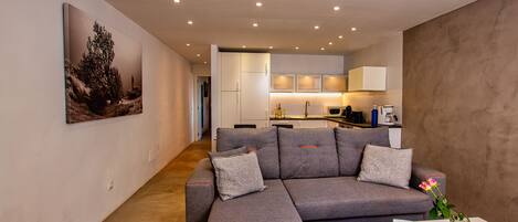Ein modernes Wohnzimmer mit einem grauen Ecksofa, einem Couchtisch und einem Gemälde an der Wand.