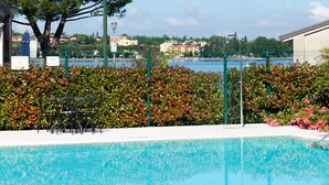 A swimming pool with a clear view of the sea and buildings in the background. - Al Fiore (Peschiera del Garda)