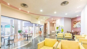 A spacious lobby with yellow seating, a glass coffee table, and a modern ceiling design. - Al Fiore (Peschiera del Garda)