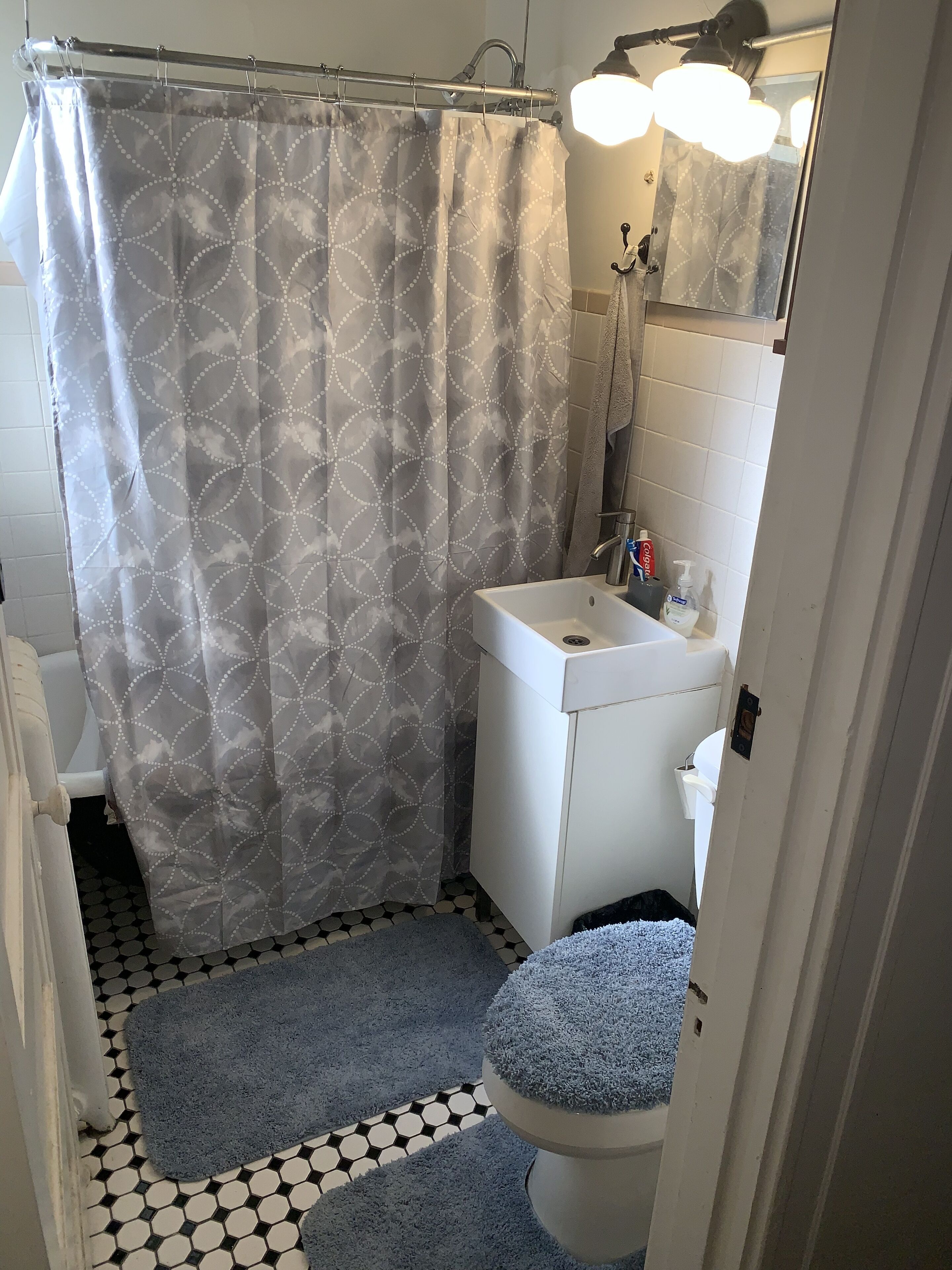 Ein Badezimmer mit Duschvorhang, Waschbecken, Spiegel und Toilette.