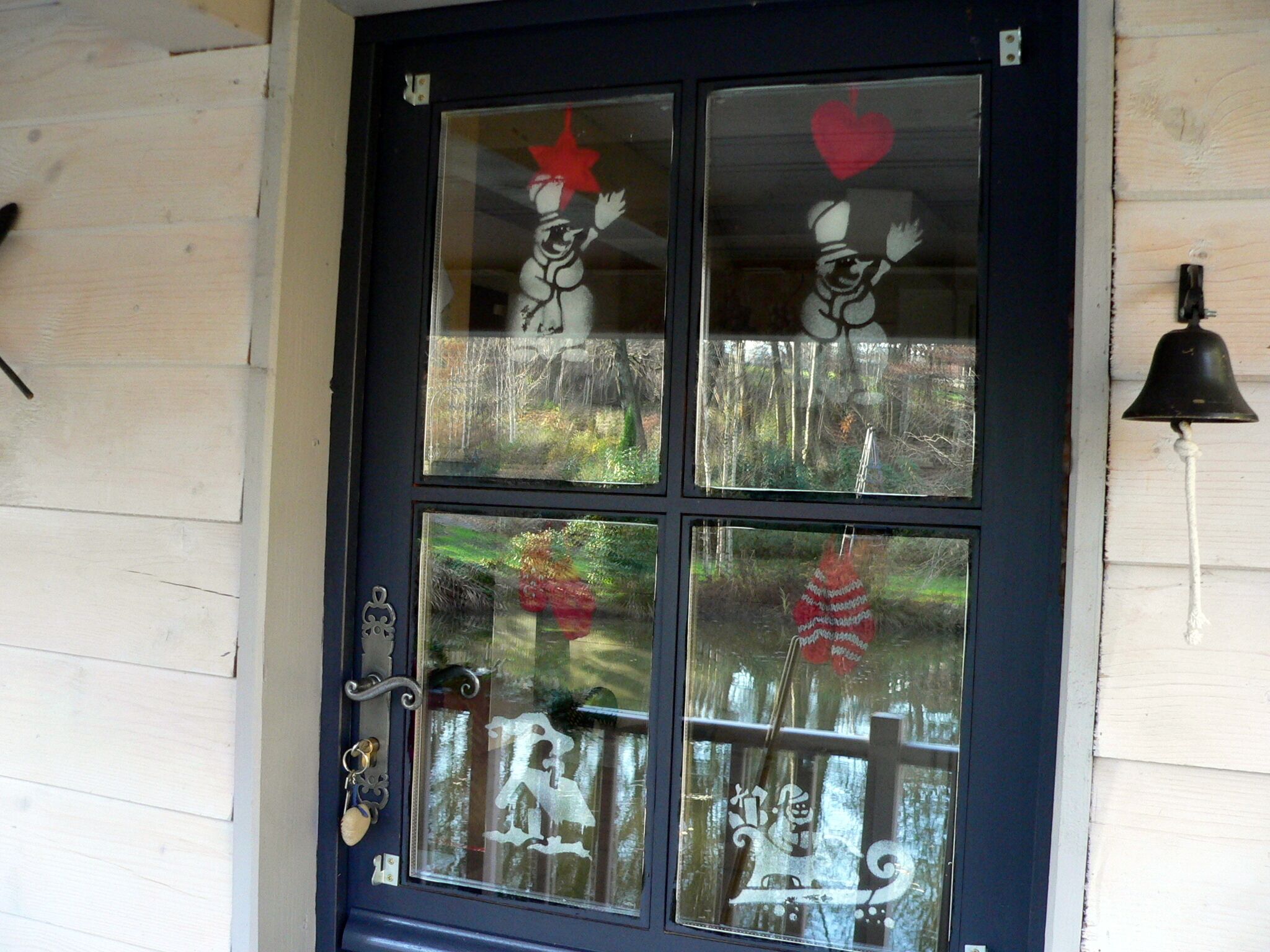 A front door with a glass panel featuring a dog, a heart, and a bell.