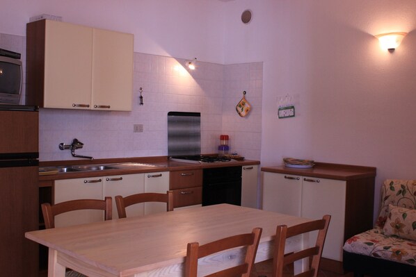 A compact kitchen with a dining area, featuring cabinets, a stove, and a sink.