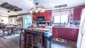 A spacious kitchen with wooden flooring, a central island, and red cabinetry. - Quiet and secluded country escape (Ashley)