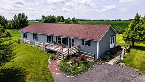A two-story house with a red roof, a front porch, and a gravel driveway. - Quiet and secluded country escape (Ashley)