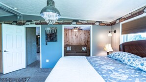 A bedroom with a large bed, a wooden headboard, a ceiling fan, a chandelier, and a nightstand with a lamp. - Quiet and secluded country escape (Ashley)
