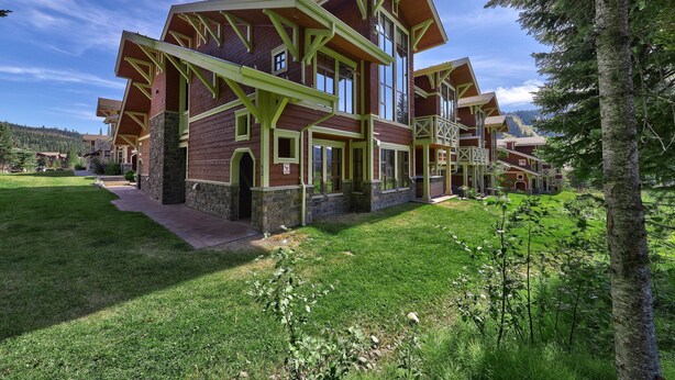 A large, multi-story building with a distinctive architectural style, featuring prominent green framing and large windows. - Rare Ski In Ski Out Top Floor Corner Unit! (Sun Peaks)